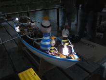 Posádka na přídi mává lucernou.